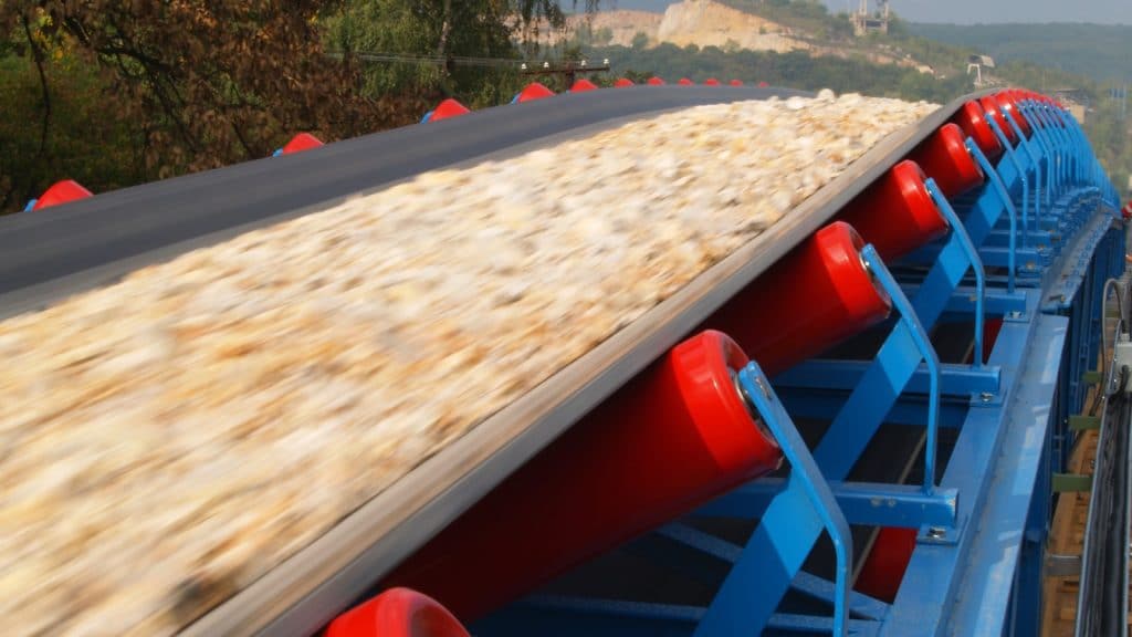 Bulk aggregate material moving along a conveyor