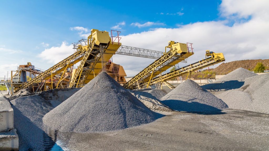 A radial stacker conveyor transporting gravel to conical piles