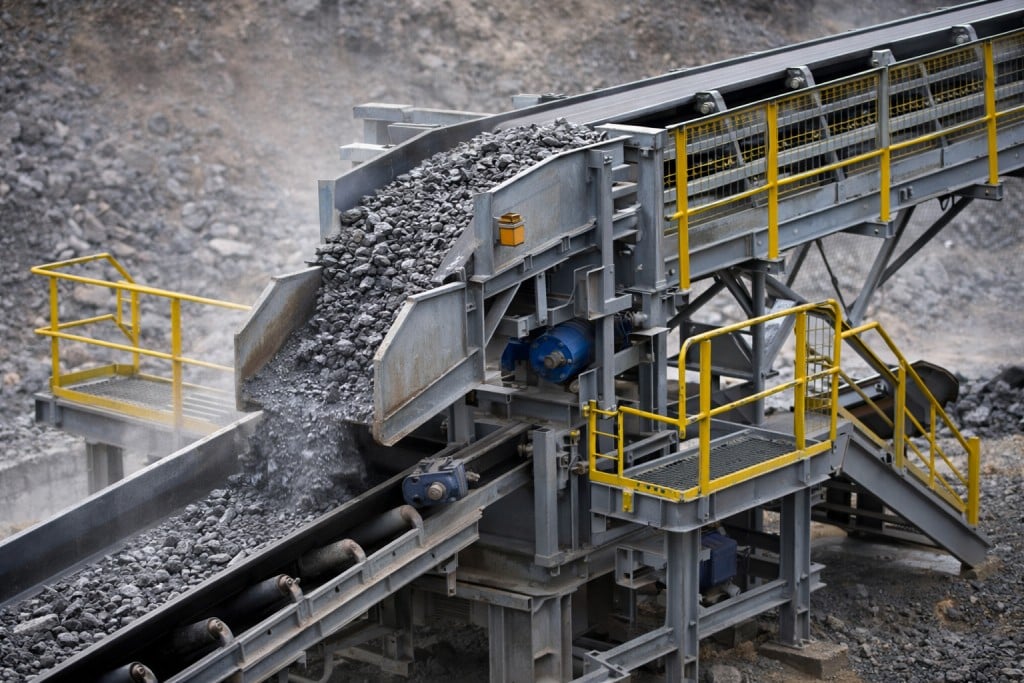 Mining conveyor transfer chute guiding bulk material between belts
